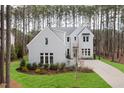 A charming grey home boasts manicured landscaping with tall trees in the background at 49 Bonterra Way, Chapel Hill, NC 27516