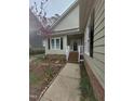Inviting front entrance with a covered porch, white railings, and beautiful landscaping leading to the front door at 4909 Willow Tree Ln, Clayton, NC 27520
