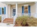 Cozy front porch featuring brick steps, white columns, blue shutters, and inviting outdoor seating at 5 Piney Park Ln, Durham, NC 27713
