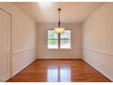 Cozy dining room featuring a window, chair rail, hardwood floors, and a modern light fixture at 524 Farmington Woods Dr, Cary, NC 27511