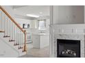 View of the kitchen from the stairs featuring white cabinets and a marble fireplace at 7201 Spanglers Spring Way, Raleigh, NC 27610