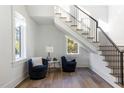 Bright foyer features hardwood floors, a staircase with iron railings, and two comfortable chairs at 4300 Camelot Dr, Raleigh, NC 27609