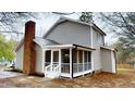 Exterior view of a home with a screened-in porch featuring white railings and brick chimney at 4604 Sweet Melody Ln, Knightdale, NC 27545