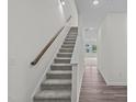 Bright entryway featuring a carpeted staircase with a wooden handrail and adjacent hardwood-style flooring at 1161 Solace Way, Rolesville, NC 27571