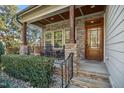 Inviting front porch features stone columns, stone accents, wood ceiling, and an outdoor seating area at 1209 Kingston Ridge Rd, Cary, NC 27511