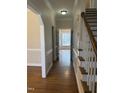 Hallway features hardwood flooring, white trim, and leads to a room filled with natural light at 1904 Baronsmede Dr, Raleigh, NC 27615
