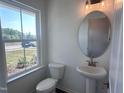 Powder room featuring a pedestal sink, oval mirror, and a window that brings in natural light at 269 Marvel Dr # 138, Rolesville, NC 27571