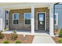 Inviting covered porch with brick accents, a black front door, and white support columns at 269 Marvel Dr # 138, Rolesville, NC 27571