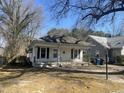 Exterior elevation of cottage-style home with a covered front porch, side driveway and mature trees at 2711 Ashe St, Durham, NC 27703
