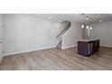 Open-concept space with wood floors, staircase, and an island with pendant lights at 280 Chesapeake Commons St # 151, Garner, NC 27529