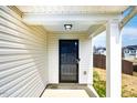 Covered front entryway featuring a black front door, white siding, and support beams at 314 Mason Trace, Burlington, NC 27217