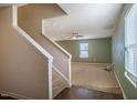 A spacious living room with neutral carpet and a ceiling fan, showcasing a staircase leading to the upper level at 314 Mason Trace, Burlington, NC 27217