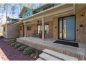 Covered porch area of a brick home with slate flooring and a modern front door at 38 Kingbird Ln, Chapel Hill, NC 27517