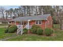 Quaint brick home with a white picket porch, surrounded by lush greenery at 461 Camp Rd, Burlington, NC 27217