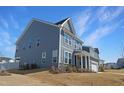 A low angle view of a two-story home featuring light blue siding, and white trimmed windows and trim at 624 Red Arrow Dr, Knightdale, NC 27545
