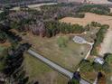 Expansive aerial view of a brick home on a large plot of land surrounded by lush trees and open fields at 6404 Pulley Town Rd, Wake Forest, NC 27587