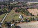 Bird's eye view of a charming house, expansive lawn, and bordering farmland, promising serene country living at 6404 Pulley Town Rd, Wake Forest, NC 27587