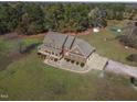 Aerial view of a brick home with a three car garage and a sprawling lawn surrounded by trees at 6404 Pulley Town Rd, Wake Forest, NC 27587