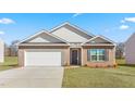 Charming single-story home featuring a brick facade, two-car garage, and neatly manicured lawn on a sunny day at 880 Forth Ct, Gibsonville, NC 27249