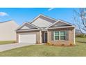 Charming single-story home featuring a brick facade, two-car garage, and neatly manicured lawn on a sunny day at 880 Forth Ct, Gibsonville, NC 27249