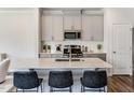 Bright kitchen boasts stainless appliances, sleek white cabinets, and a spacious island with barstool seating at 1042 Sweet Woodruff Dr, Zebulon, NC 27597