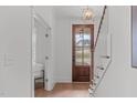 Bright foyer showcasing a wood door with glass, hardwood floors, staircase, and a modern light fixture at 116 Pointe Park Cir, Holly Springs, NC 27540