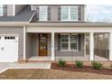 Inviting front porch with white columns, a wood door, and a well-maintained front lawn with fresh mulch at 116 Pointe Park Cir, Holly Springs, NC 27540