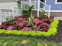 Vibrant landscaping with colorful flowers and lush greenery surrounds the base of the front porch stairs at 2245 Dunlin Ln, Raleigh, NC 27614