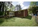 View of the back of the house, including the enclosed porch, the air conditioning unit, and the surrounding yard at 2726 Thelma St, Durham, NC 27704