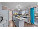 A traditionally styled kitchen features gray cabinets, a center island, a view to the backyard, and access to dining at 300 Pate St, Apex, NC 27502