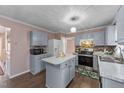 A traditionally styled kitchen features gray cabinets, a center island, and stainless steel appliances at 300 Pate St, Apex, NC 27502