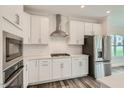 Modern kitchen featuring white cabinetry, stainless steel appliances, tile backsplash, and wood-look floors at 624 Emerald Bay Cir, Raleigh, NC 27610