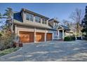 View of a spacious three-car garage featuring wooden doors, ample parking, and convenient access to the home at 805 Greenwood Rd, Chapel Hill, NC 27514