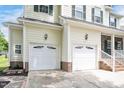 Spacious two-car garage with white doors, exterior lighting, and brick base in a bright home at 1106 Bellenden Dr, Durham, NC 27713