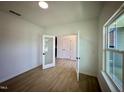 Bedroom features light wood floors, white walls, a large window, and an open doorway at 130 W Crescent Mills Blvd # Homesite 251, Wilson's Mills, NC 27520