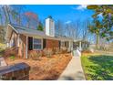 Charming brick home featuring a walkway, chimney, manicured landscaping, and an inviting front porch at 1405 N Sellars Mill Rd, Burlington, NC 27217