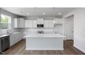 Bright kitchen features white cabinetry, stainless steel appliances, large island, and wood-look flooring at 173 Wild Turkey Way, Lillington, NC 27546