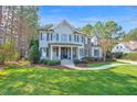 Beautiful exterior of home with lush landscaping and stone detailing; blue paint and black shutters at 204 Dartmoor Ln, Raleigh, NC 27614