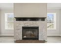Cozy fireplace with stone surround and black mantel, flanked by windows at 248 Dutches Ln, Henderson, NC 27537