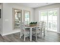 Bright dining area with wood-look flooring, a modern table set, and sliding door access to the outdoors at 26 Artesa Ct, Fuquay Varina, NC 27526