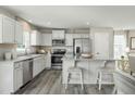 Stylish kitchen features white cabinets, stainless steel appliances, and a convenient center island with bar stool seating at 26 Artesa Ct, Fuquay Varina, NC 27526