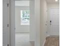 Bright hallway featuring wood-look flooring and neutral walls, leading to a room with a window at 267 Palm Dr, Sanford, NC 27332