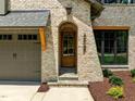Arched wood front door with glass, flanked by beige brick and a three car garage at 3727 Bellevue Rd, Raleigh, NC 27609