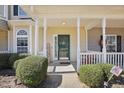 Inviting front porch with welcoming decor, green door, and manicured shrubs at 3809 Volkswalk Pl, Raleigh, NC 27610