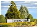 Community sign surrounded by lush landscaping featuring mature trees and colorful flower beds at 5818 Humanity Ln, Raleigh, NC 27616