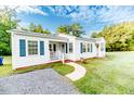 Quaint home with walkway, landscaping, and blue shutters on a beautiful sunny day at 201 Colonial Ave, Goldston, NC 27252