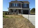 New construction gray home with a two car garage, covered porch and professionally staged bare front lawn at 22 Wynd Crest Way, Benson, NC 27504
