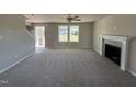 Bright, open living room with neutral carpet, a fireplace, a ceiling fan, and abundant natural light at 22 Wynd Crest Way, Benson, NC 27504