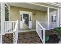 Inviting front porch with brick steps, white railings, and a stylish glass door with side windows at 2208 Woodbury Dr, Hillsborough, NC 27278