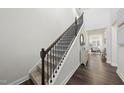 Elegant staircase with hardwood floors, white walls, dark wood railing, and natural light at 225 Ivy Arbor Way, Holly Springs, NC 27540